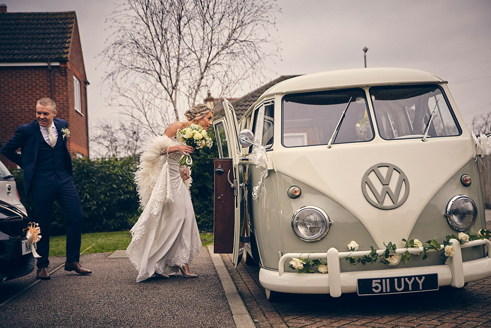 Bride entering a VW campervan on the way to her wedding