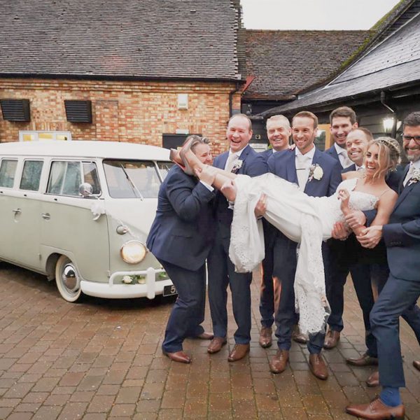 Groomsmen lift the bride for a photo