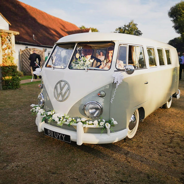 Bride and groom sit in the front of a VW camper