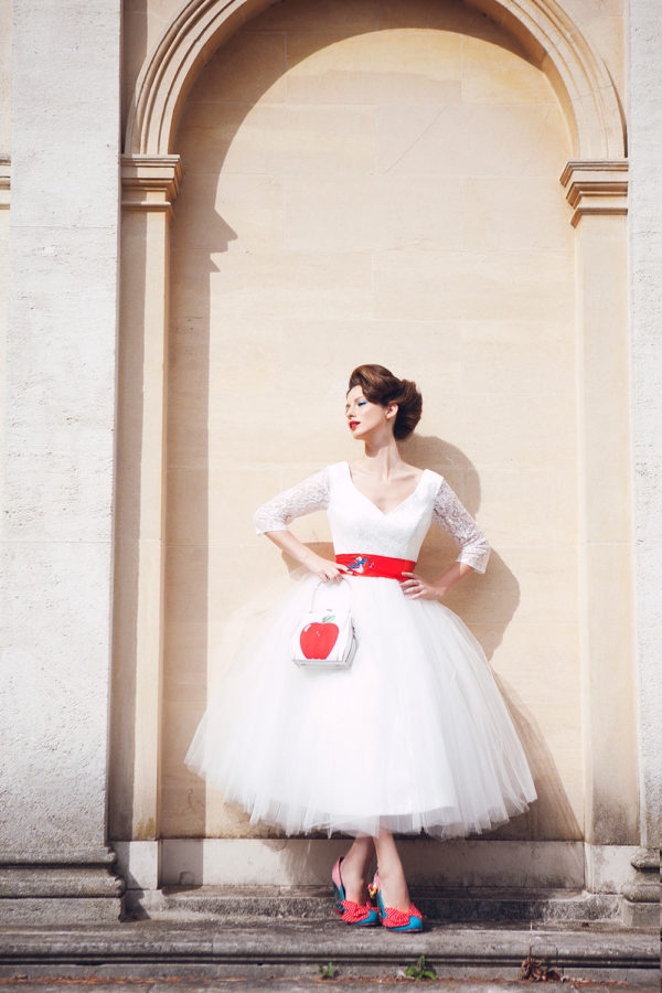 Tea length, ivory lace and tulle gown with red satin sash tied around waist