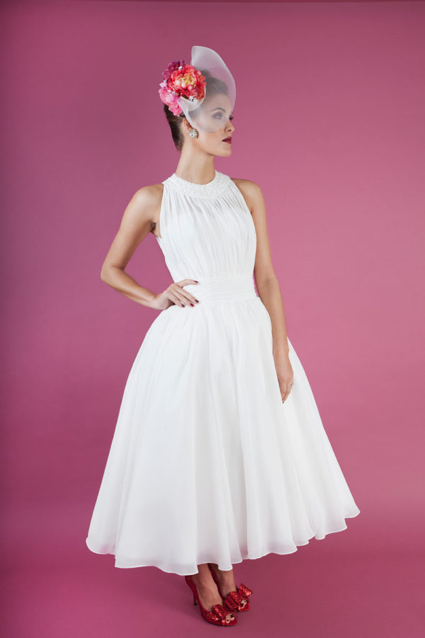 Tea-length bridal gown with sequin and beaded neckline and pleated ivory chiffon.